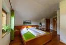 Gemütliches Dachgeschoss-Zimmer mit Holzbett, Bademantel und alpinem Alm-Motiv