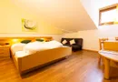 Doppelzimmer mit Holzbett, gelber Wand, Sofa und Sitzecke unter der Dachschräge