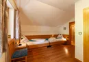 Gemütliches Zweibettzimmer mit Holzbetten und Fenster im alpinen Stil