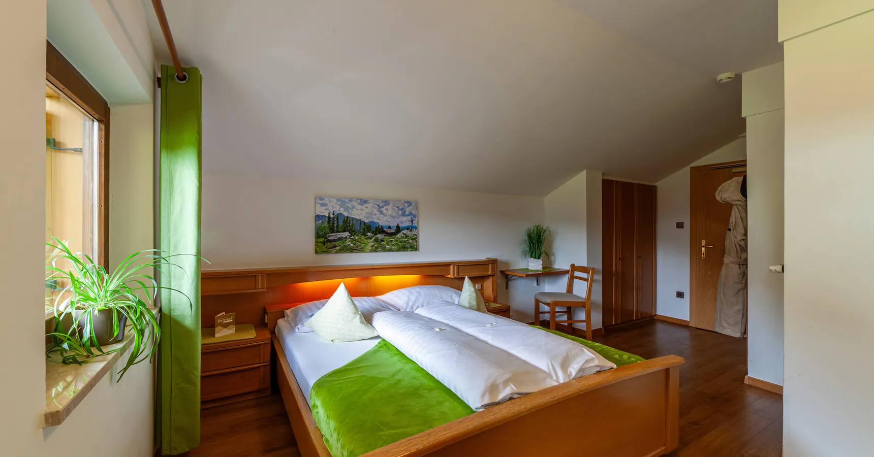 Gemütliches Dachgeschoss-Zimmer mit Holzbett, Bademantel und alpinem Alm-Motiv
