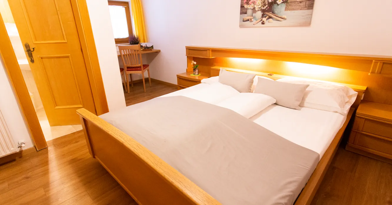 Doppelzimmer mit Holzbett und Schreibtischbereich im Almhotel Bergerhof