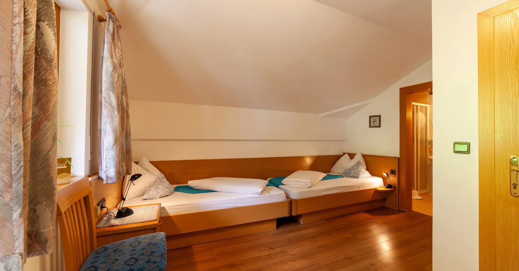 Gemütliches Zweibettzimmer mit Holzbetten und Fenster im alpinen Stil