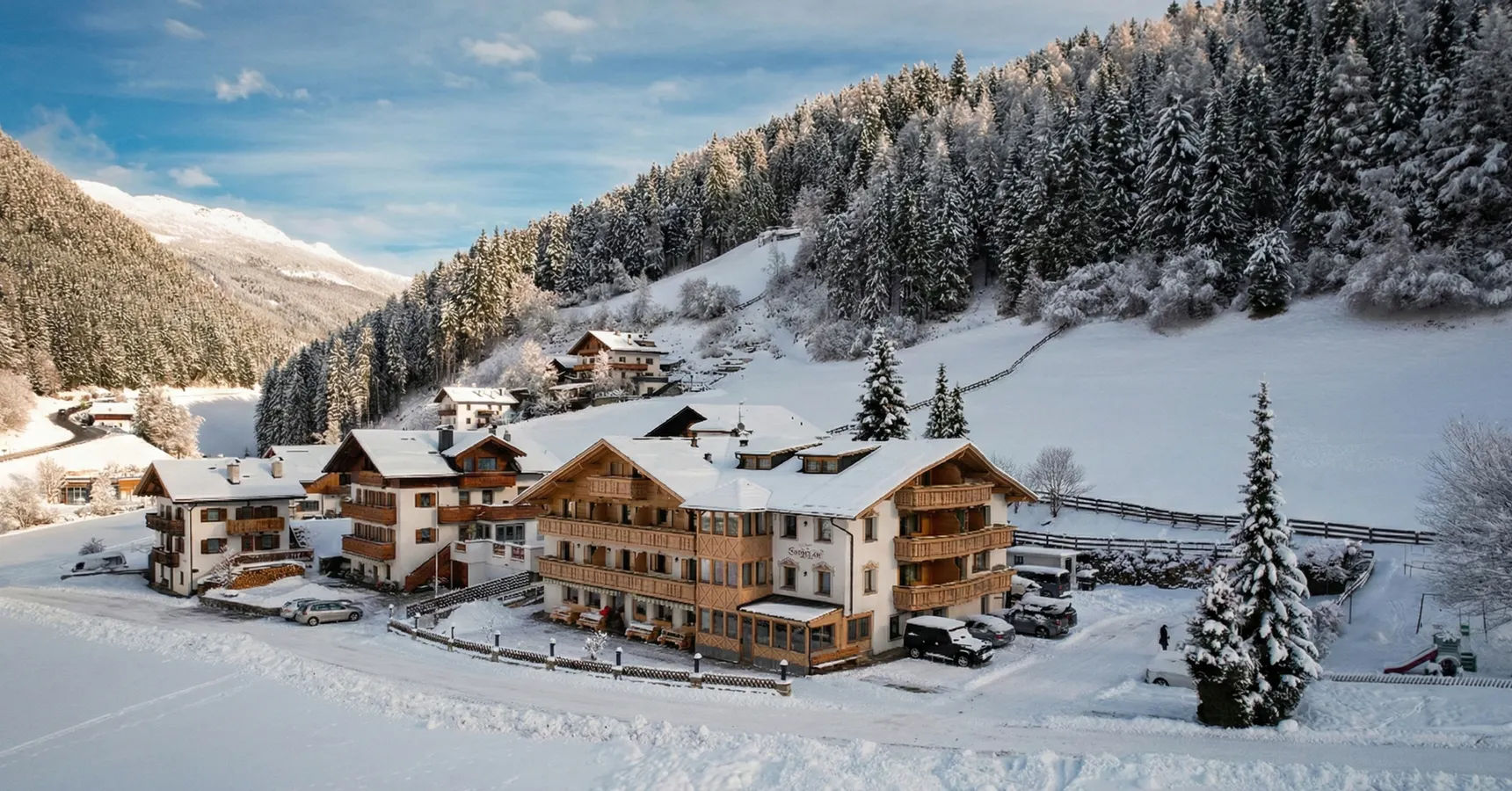 Almhotel Bergerhof im tief verschneiten Sarntal mit schneebedeckten Wäldern und Bergen