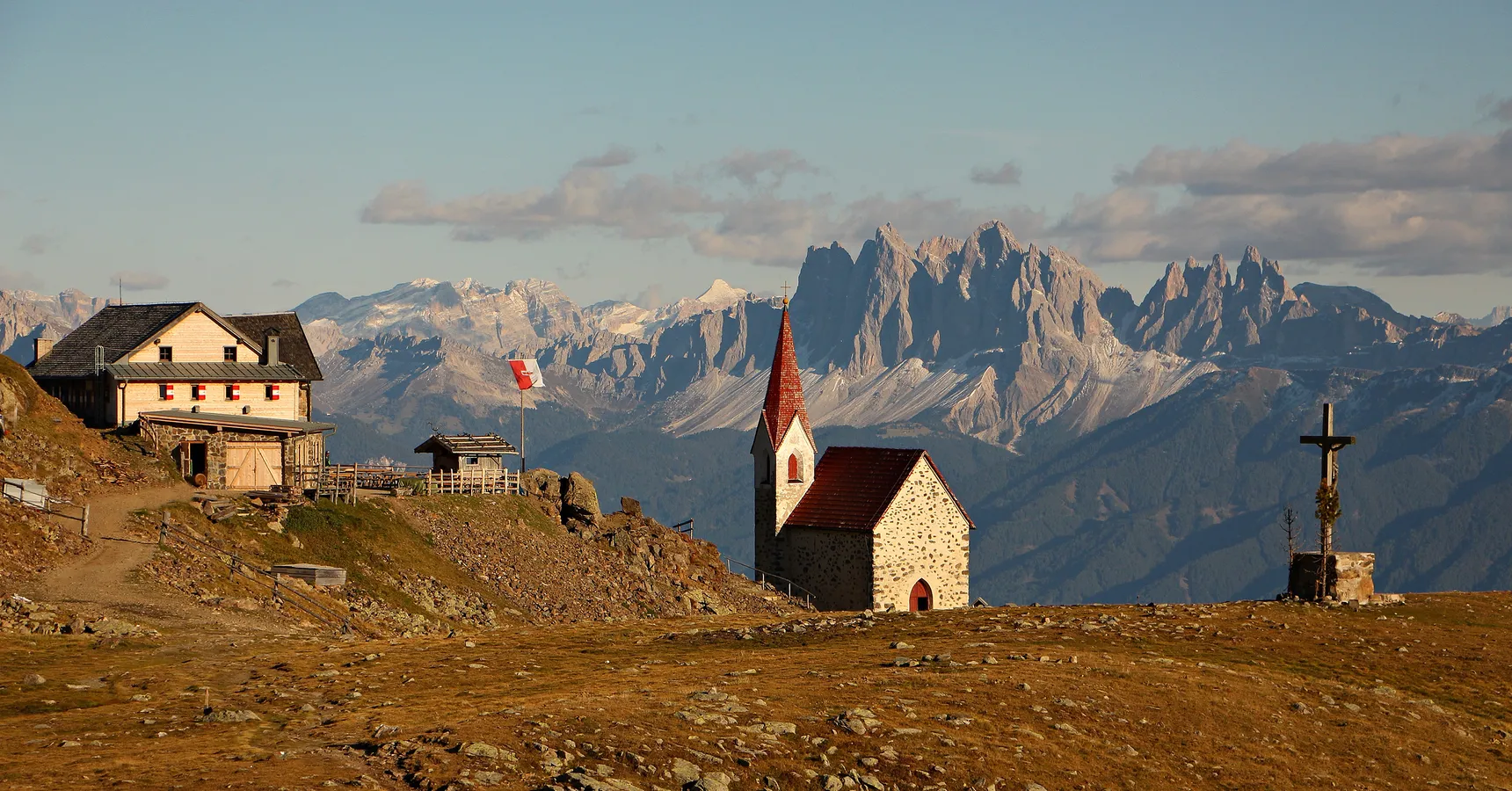 Latzfonser Kreuz mit Schutzhütte und Bergkapelle vor Dolomitenpanorama im Abendlicht