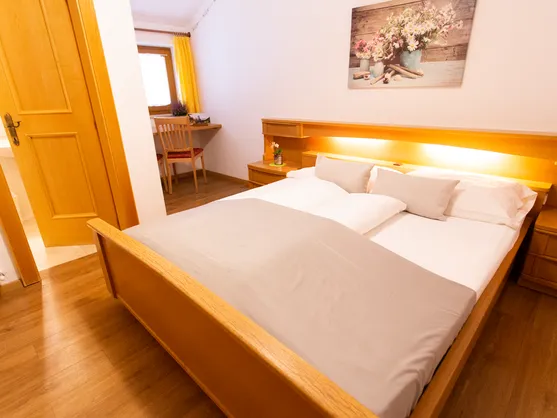 Doppelzimmer mit Holzbett und Schreibtischbereich im Almhotel Bergerhof