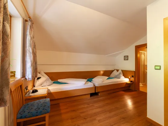 Gemütliches Zweibettzimmer mit Holzbetten und Fenster im alpinen Stil