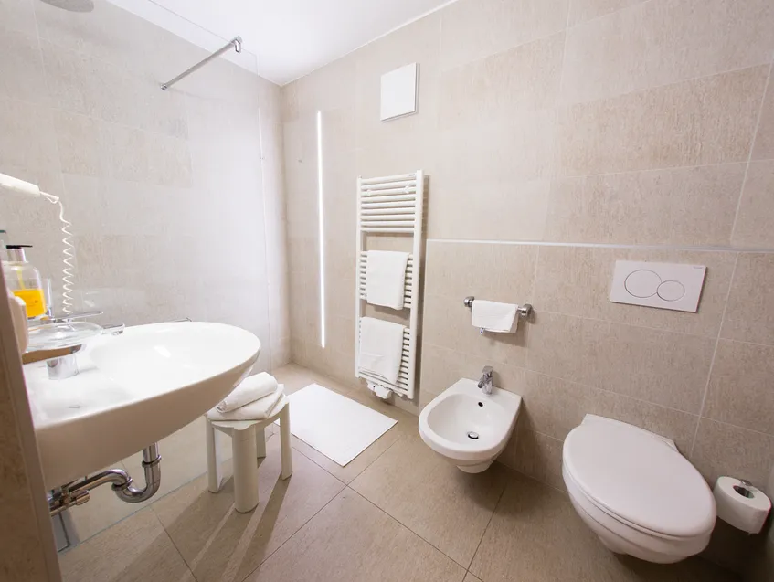 Modernes Badezimmer mit beigen Fliesen, Bidet, wandhängendem WC und bodengleicher Dusche