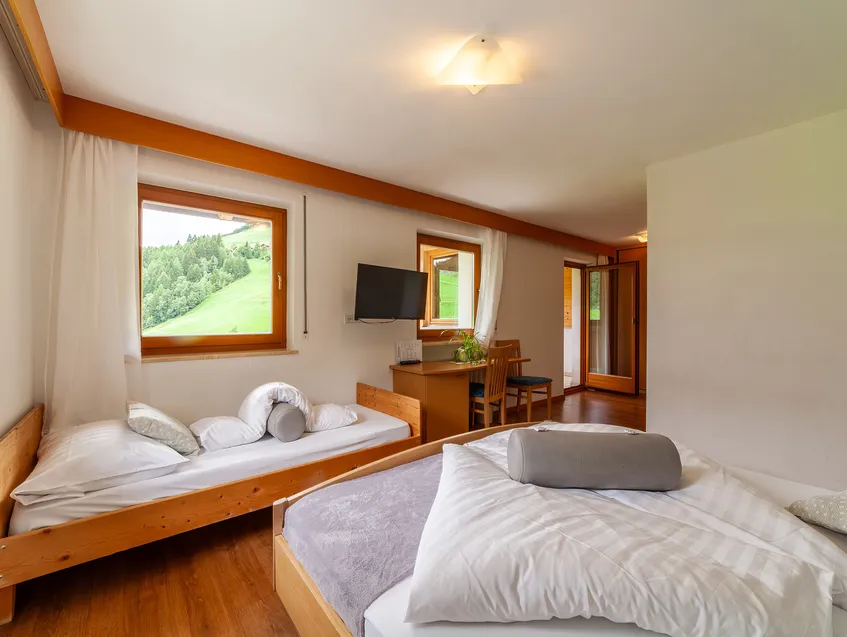 Dreibettzimmer mit Doppelbett und Einzelbett, Fenster mit Blick auf Almwiesen im Sarntal