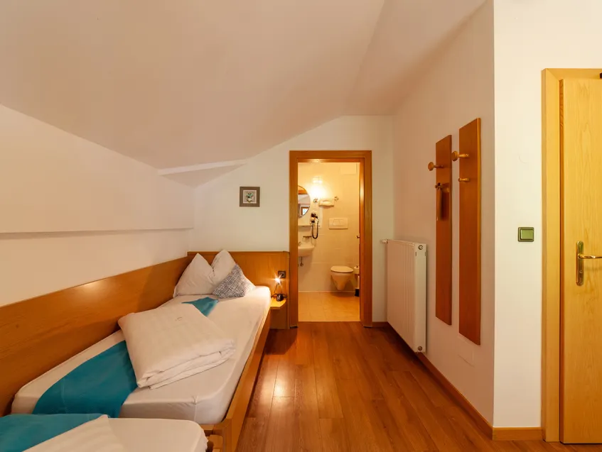 Zimmer mit zwei Einzelbetten und angrenzendem Bad im alpinen Stil