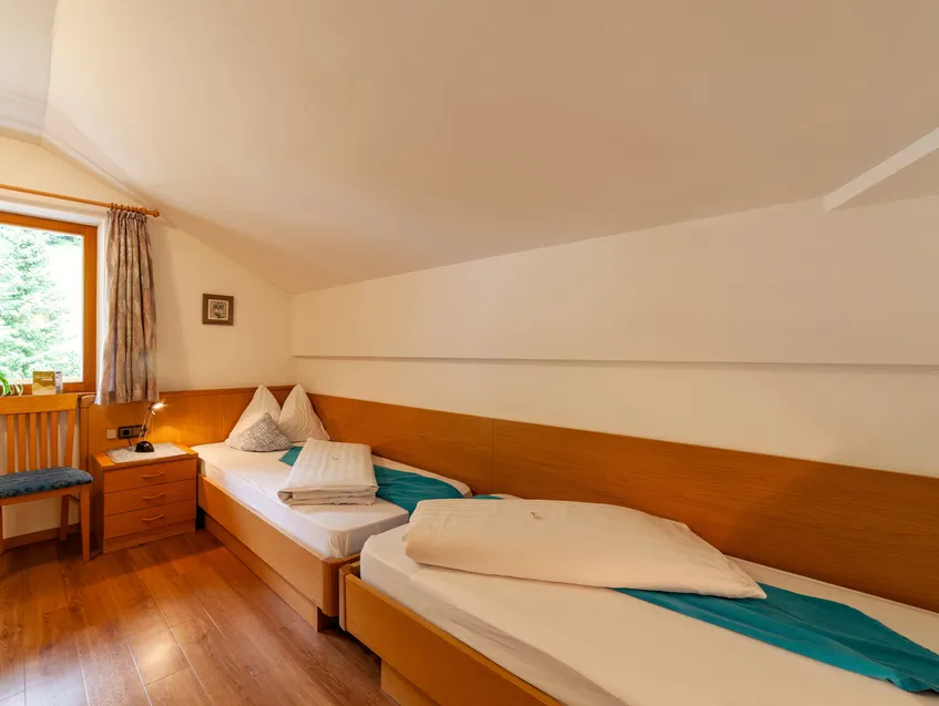 Helles Zweibettzimmer mit Holzmöbeln und Blick ins Grüne im Sarntal