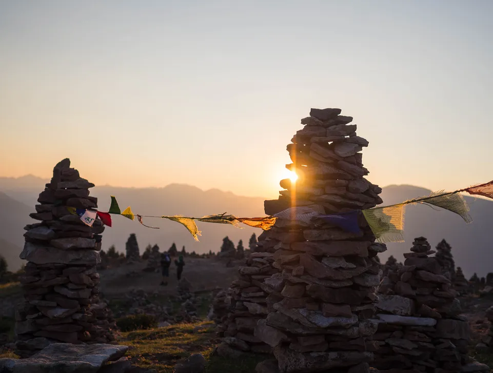 Steinmännchen mit bunten Gebetsfahnen im goldenen Sonnenuntergang, meditative Bergstimmung